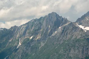 Beautiful mountain range with snow caps under cloudy skies, showcasing rugged natural beauty. jigsaw puzzle