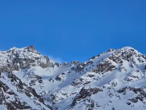 Majestic snow-covered mountain peaks against a clear blue sky, capturing the serene beauty of winter. jigsaw puzzle