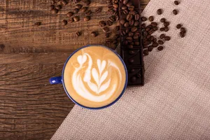 Overhead view of a latte with swan latte art, surrounded by coffee beans and chocolate on rustic wood. jigsaw puzzle
