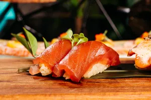Delicious slices of salmon nigiri sushi served beautifully on a wooden platter with garnish. jigsaw puzzle