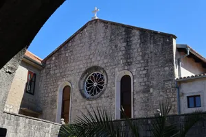 A beautiful stone church facade with a cross and arched windows under a bright blue sky. jigsaw puzzle