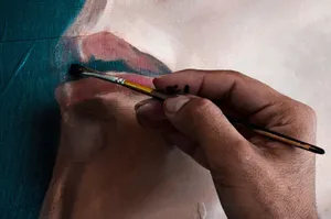 A detailed view of a hand using a paintbrush to create a portrait on canvas, showcasing artistic creativity. jigsaw puzzle