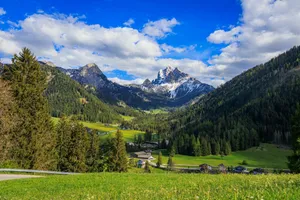 Majestic mountains overlook a lush green valley with scattered houses. jigsaw puzzle