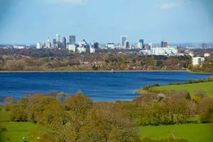City skyline across a blue lake and green hills jigsaw puzzle