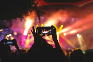 person holding smartphone taking video of a concert near stage with lights during nighttime jigsaw puzzle