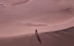 Aerial view of a lone person standing on vast sand dunes in Dubai's desert landscape. jigsaw puzzle