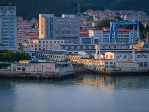 A scenic view of city buildings and industrial structures along a calm waterfront during dusk. jigsaw puzzle