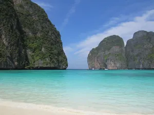 Tranquil tropical beach in Thailand featuring clear turquoise waters and lush cliffs. jigsaw puzzle