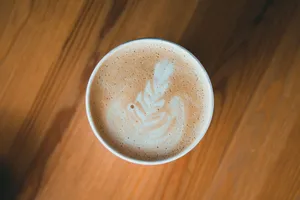 Top-view close-up of intricate latte art in a frothy coffee cup on a wooden table. jigsaw puzzle