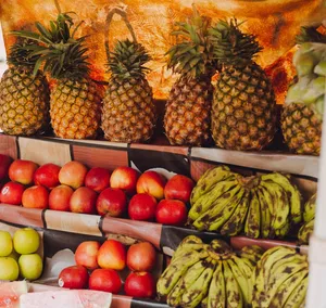 A colorful display of pineapples, apples, and plantains at a fruit market stand. jigsaw puzzle