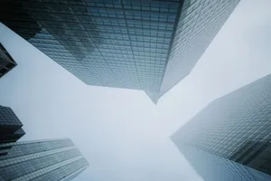 Low angle view of modern glass skyscrapers disappearing into the foggy sky, creating a dramatic urban scene. jigsaw puzzle