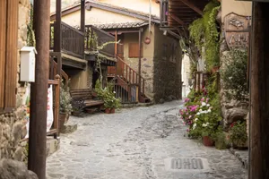 Charming cobblestone alleyway with flowers and wooden benches in Kakopetria, Cyprus. jigsaw puzzle