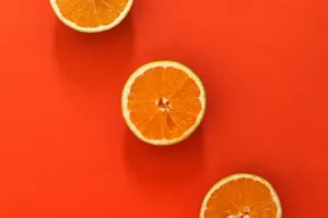 Three juicy orange slices set against a vivid red background, perfect for food-themed designs. jigsaw puzzle