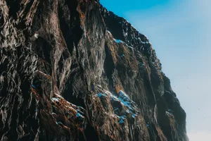 Picturesque view of light blue cloudless sky above majestic dark brown steep mountain covered with snow in daylight jigsaw puzzle