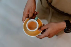 A person holding a ceramic cup with freshly brewed espresso, photographed from above. jigsaw puzzle