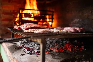 A warm close-up view of meats grilling over fiery coals on a barbecue, creating a cozy cooking ambiance. jigsaw puzzle