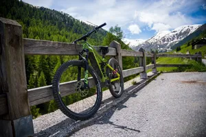 A mountain bike resting against a wooden fence with stunning snowcapped Alps in Livigno, Italy. jigsaw puzzle