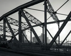 Black and white city skyline viewed through intricate steel bridge framework. jigsaw puzzle