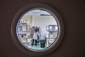 A female scientist in a lab coat working inside a state-of-the-art laboratory through a circular window view. jigsaw puzzle
