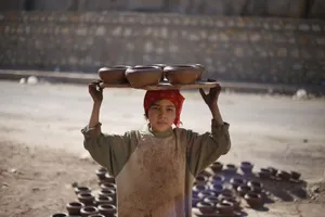 A child craftsman in Cairo carrying handmade pottery outdoors. jigsaw puzzle