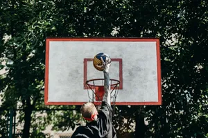 A man jumps to dunk a basketball outdoors, displaying athletic energy and skill. jigsaw puzzle