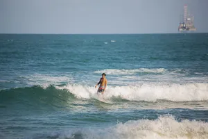 A surfer riding waves near an offshore rig, embodying adventure and nature's power. jigsaw puzzle