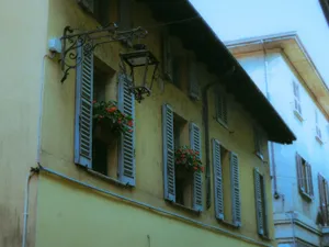 A picturesque view of a yellow house with shutters and floral decorations in an urban setting. jigsaw puzzle