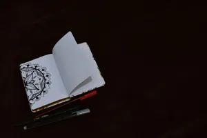 An open sketchbook with detailed doodle art next to pens on a dark surface, offering artistic inspiration. jigsaw puzzle