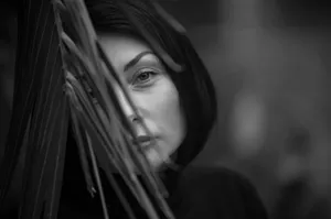 Artistic black and white portrait of a woman partially obscured by leaves, creating a mysterious look. jigsaw puzzle