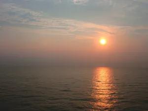 the sun is setting over the ocean on a cloudy day jigsaw puzzle