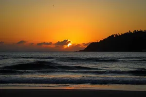 A breathtaking sunrise over the ocean with waves and a silhouette of a headland in Brazil. jigsaw puzzle