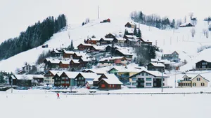 Idyllic snow-covered village nestled in winter landscape with skier in red jacket enjoying the scenery. jigsaw puzzle