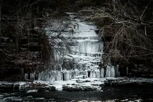 a frozen waterfall surrounded by trees and snow jigsaw puzzle