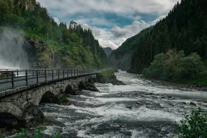 A stone bridge crosses a river in a mountainous valley. jigsaw puzzle