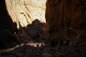 Hikers walk through a narrow canyon with a river. jigsaw puzzle