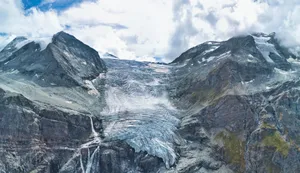 Majestic glacier flowing down rocky mountains under clouds jigsaw puzzle