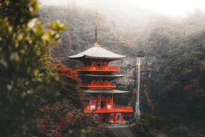 Red pagoda nestled beside a misty waterfall in autumn. jigsaw puzzle