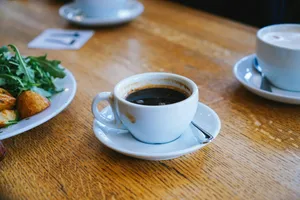 a cup of coffee and a plate of food on a table jigsaw puzzle