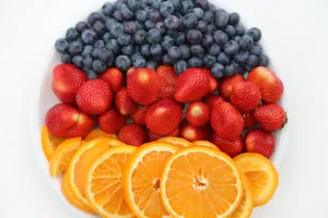 a white plate topped with oranges, blueberries and strawberries jigsaw puzzle