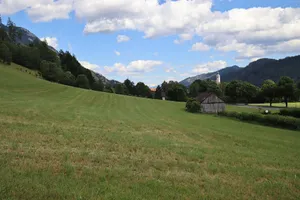 Peaceful landscape of Austrian countryside featuring a historic church and open fields under a blue sky. jigsaw puzzle