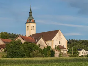 A picturesque view of a European church amidst lush greenery under a clear blue sky. jigsaw puzzle