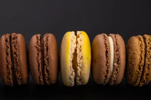 Top view of yummy sweet macaroons with cream arranged in row on black background jigsaw puzzle
