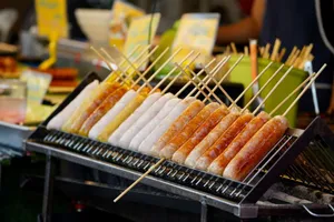 Close-up of assorted sausages on a grill at a bustling street food market. jigsaw puzzle