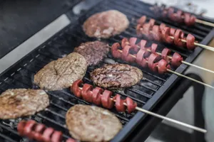 Close-up of grilled burgers and sausage skewers cooking on a barbecue grill outdoors. jigsaw puzzle