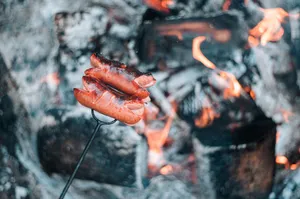 Juicy sausages grilling over open flames on a charcoal barbecue, perfect for outdoor cooking. jigsaw puzzle