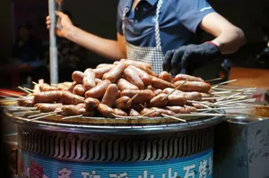 Street food vendor grilling sausages on skewers in vibrant night market setting. jigsaw puzzle