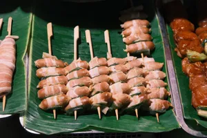 Delicious grilled sausages wrapped in bacon on skewers displayed on banana leaves. jigsaw puzzle