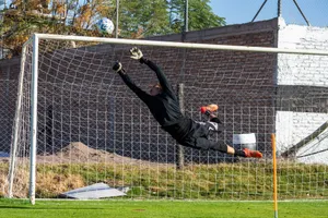 Dynamic action shot of a goalkeeper making a high save during a soccer game outdoors. jigsaw puzzle