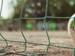 Ground level of green soccer net on rough terrain near ball on blurred background jigsaw puzzle