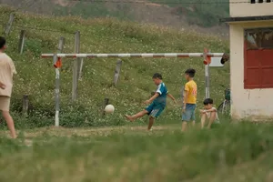 Boys enjoying a casual soccer game outdoors in a rural setting. jigsaw puzzle